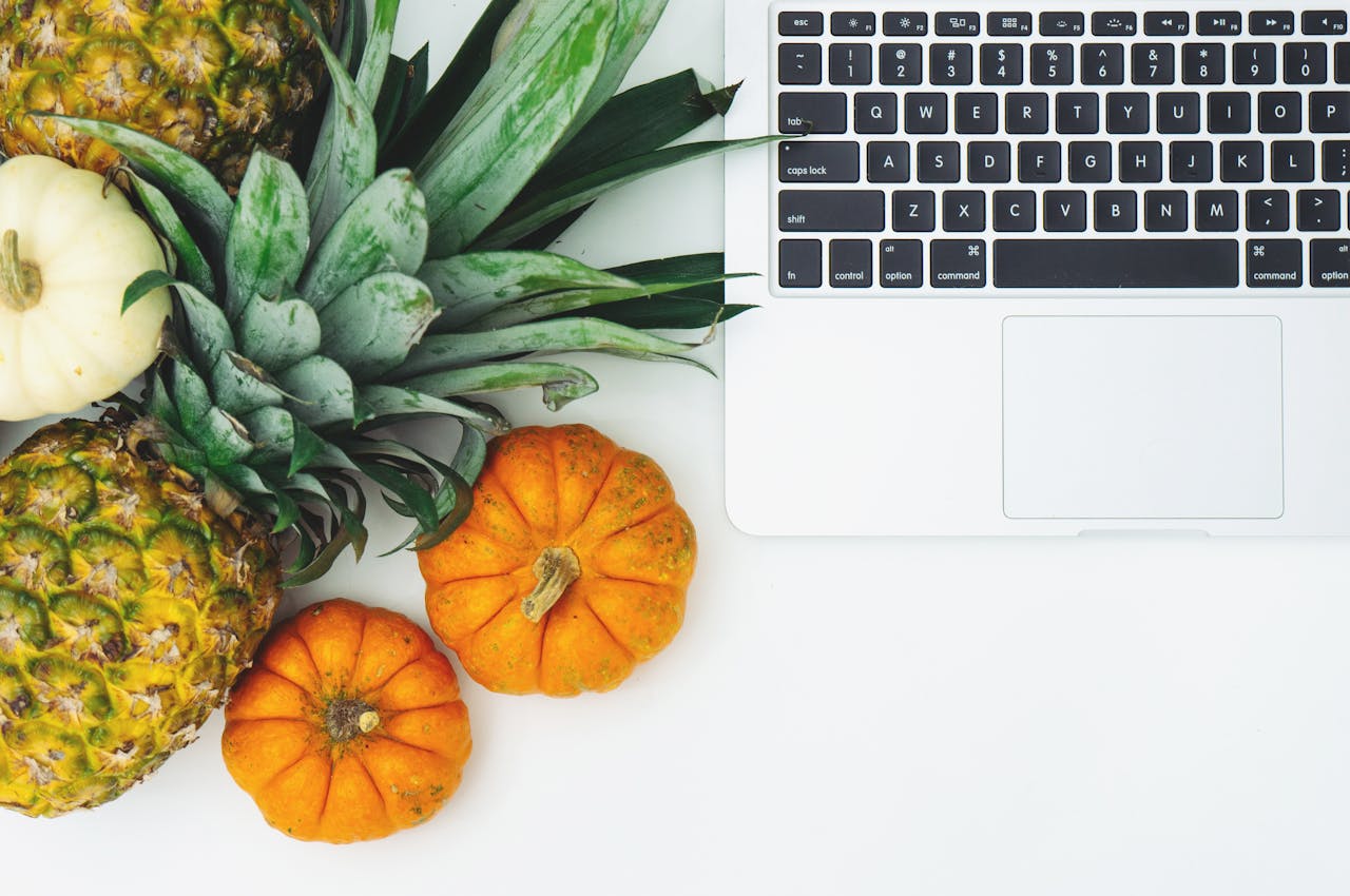 Pumpkins and Pineapple Next to Laptop